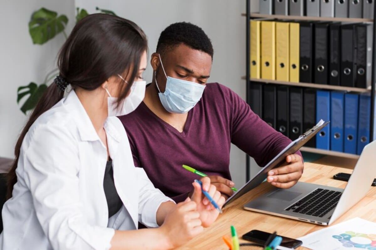 Duas pessoas com roupas de profissionais da saúde conversando sobre gestão de compras hospitalares.