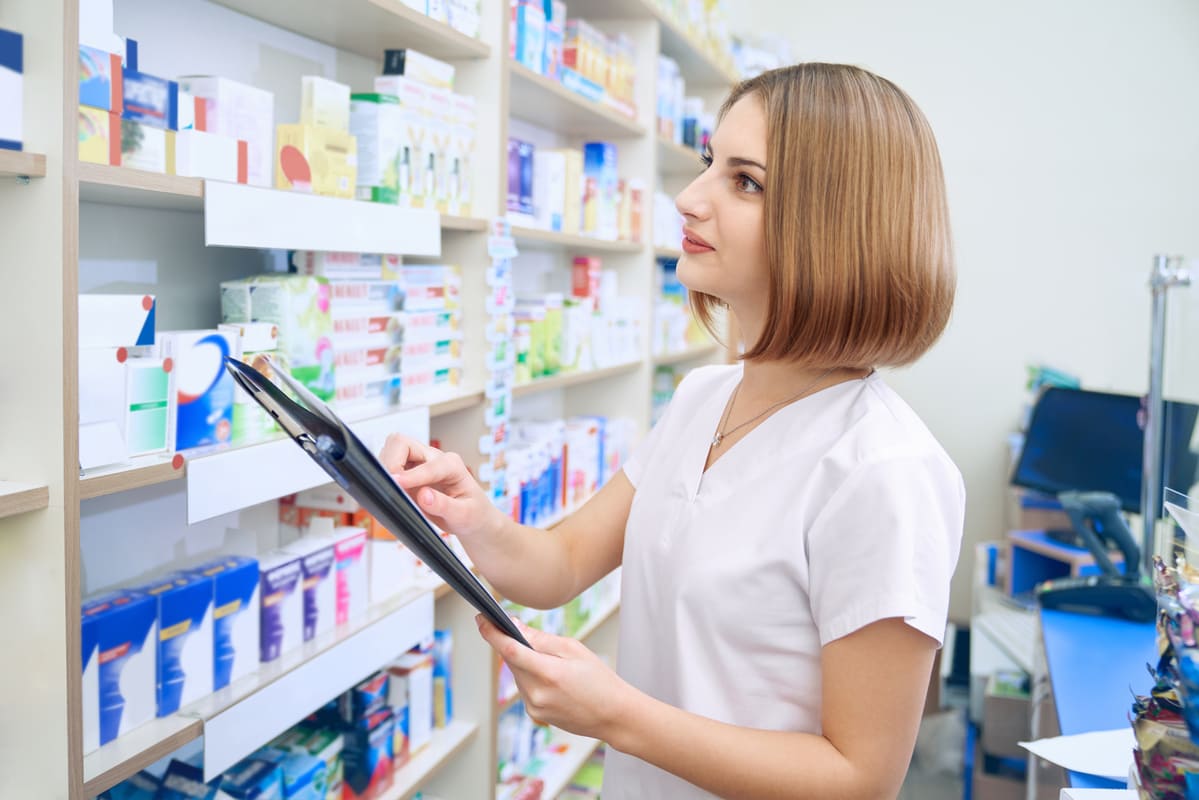 Farmacêutica conferindo estoque de medicamentos, representando a importância dos fornecedores de medicamentos para farmácias.