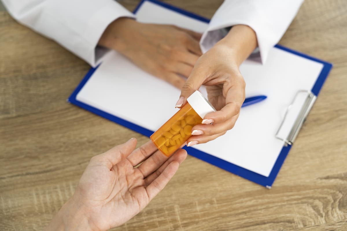 Profissional de saúde entregando um frasco de medicamentos controlados a um paciente, destacando a importância da orientação no uso seguro.