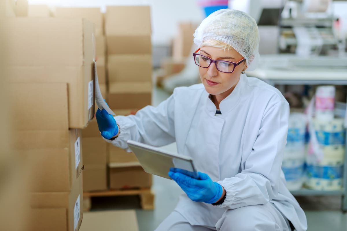 Profissional em logística hospitalar conferindo produtos e registrando informações com tablet.