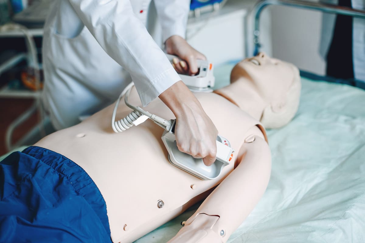 enfermeiro usando um desfibrilador em um boneco